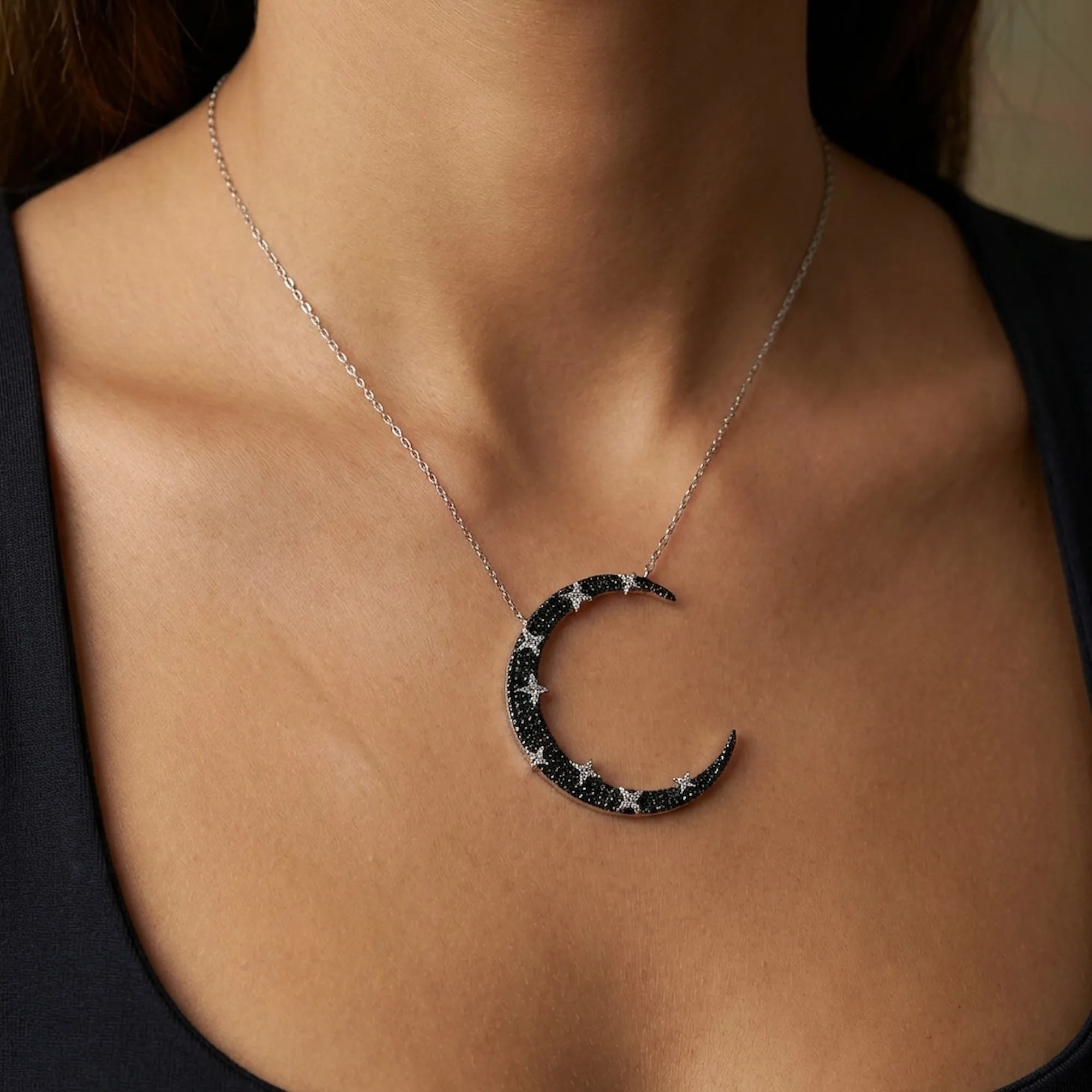 Female model wearing the sterling silver moon necklace dubai on her collarbone to demonstrate the 37mm statement pendant size and fit.