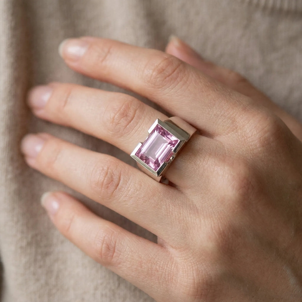 model Hand wearing a ring with a pink gemstone against a neutral background, Size reference  