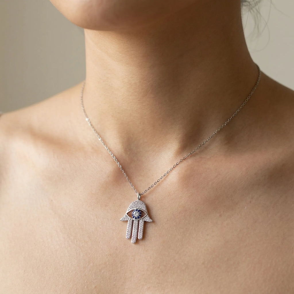 Necklace with a hamsa hand pendant on a model neck against a neutral background
