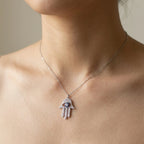 Necklace with a hamsa hand pendant on a model neck against a neutral background