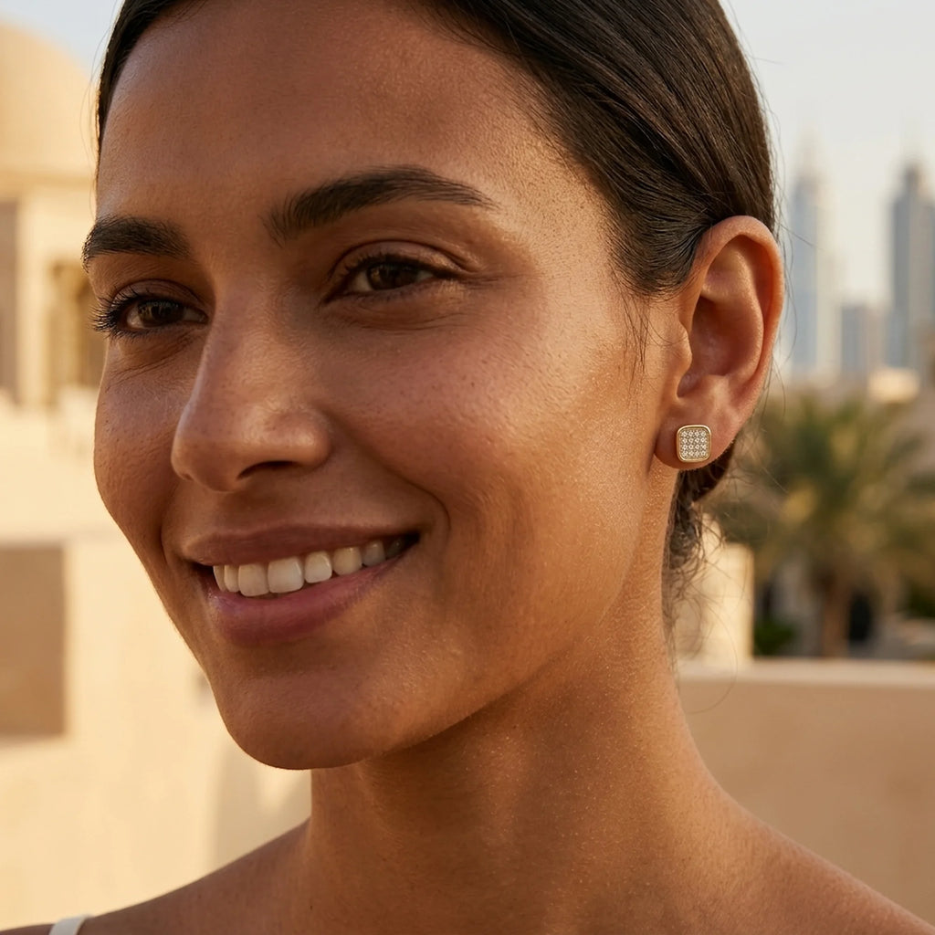 Gold mosaic pavé cubic zirconia stud earring worn on the ear with Dubai skyline behind — 925 sterling silver