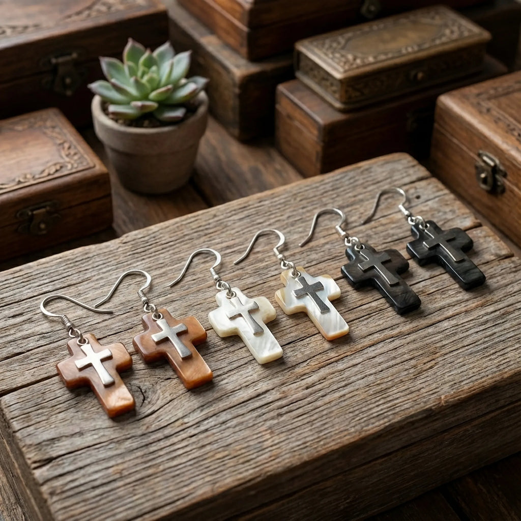  Three natural shell cross earring variants on rustic wood surface — white, black and brown Mother of Pearl with 925 silver crucifix Dubai