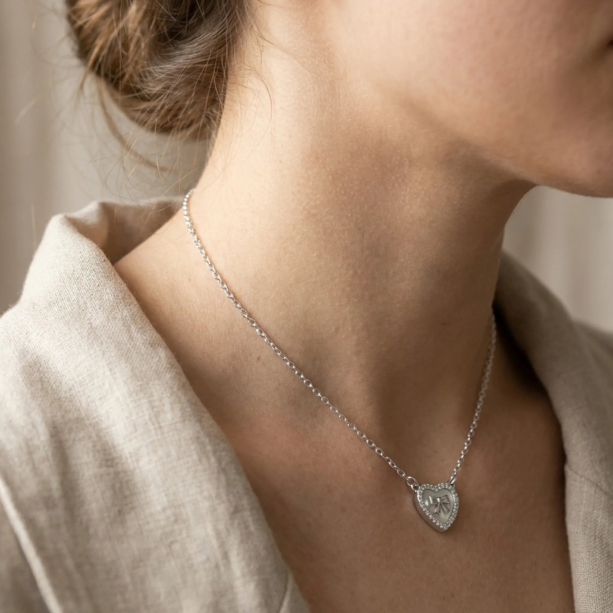 Mother of Pearl bow heart necklace on model neck showing 40cm chain fall and collarbone placement — rhodium silver 925 Dubai