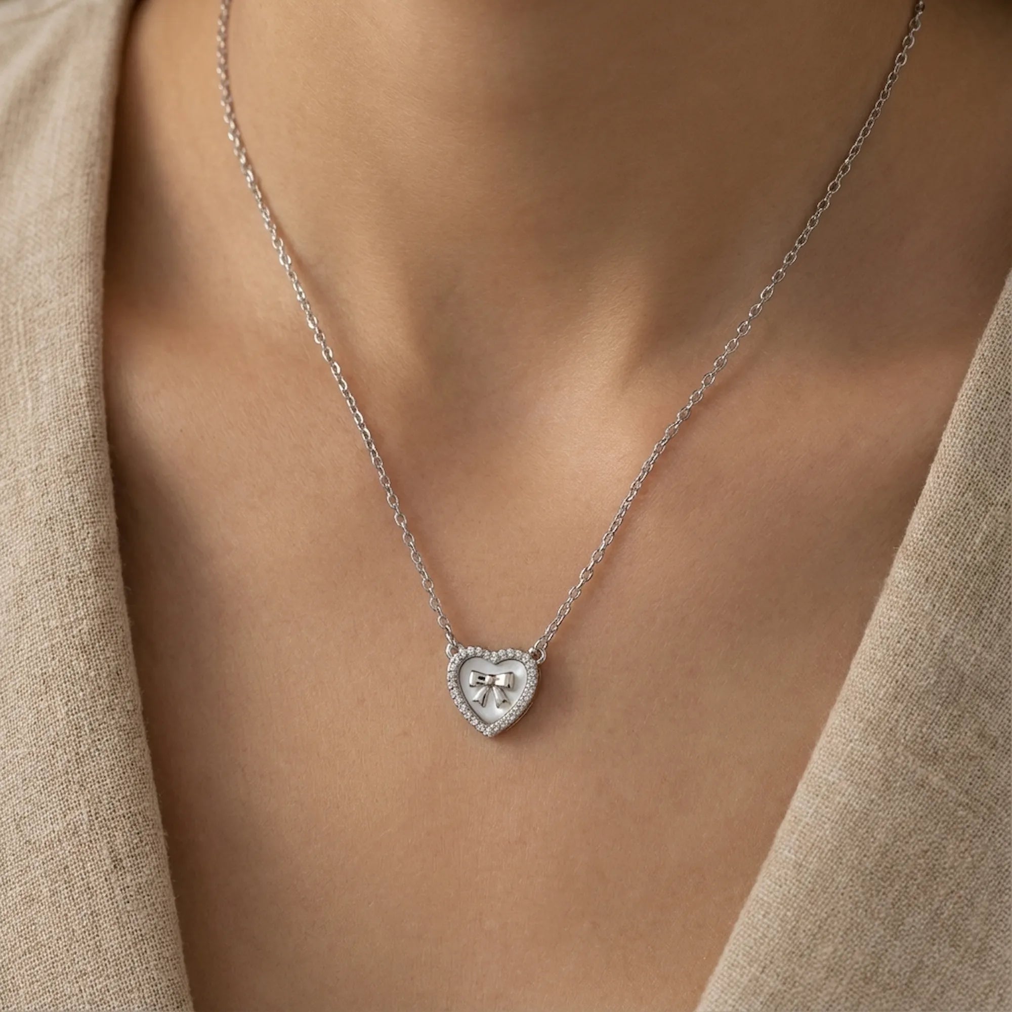 Mother of Pearl bow heart necklace on model neck showing 40cm chain fall and collarbone placement — rhodium silver 925 Dubai