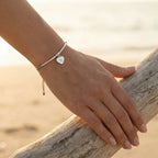 Silver North Star heart bracelet on the wrist at the Kite beach at golden hour, grey cord, Luna Dura Dubai