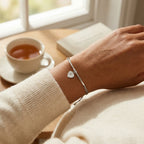 North Star heart silver bracelet on the wrist beside a cup of tea, casual weekend styling, Dubai DIFC UAE