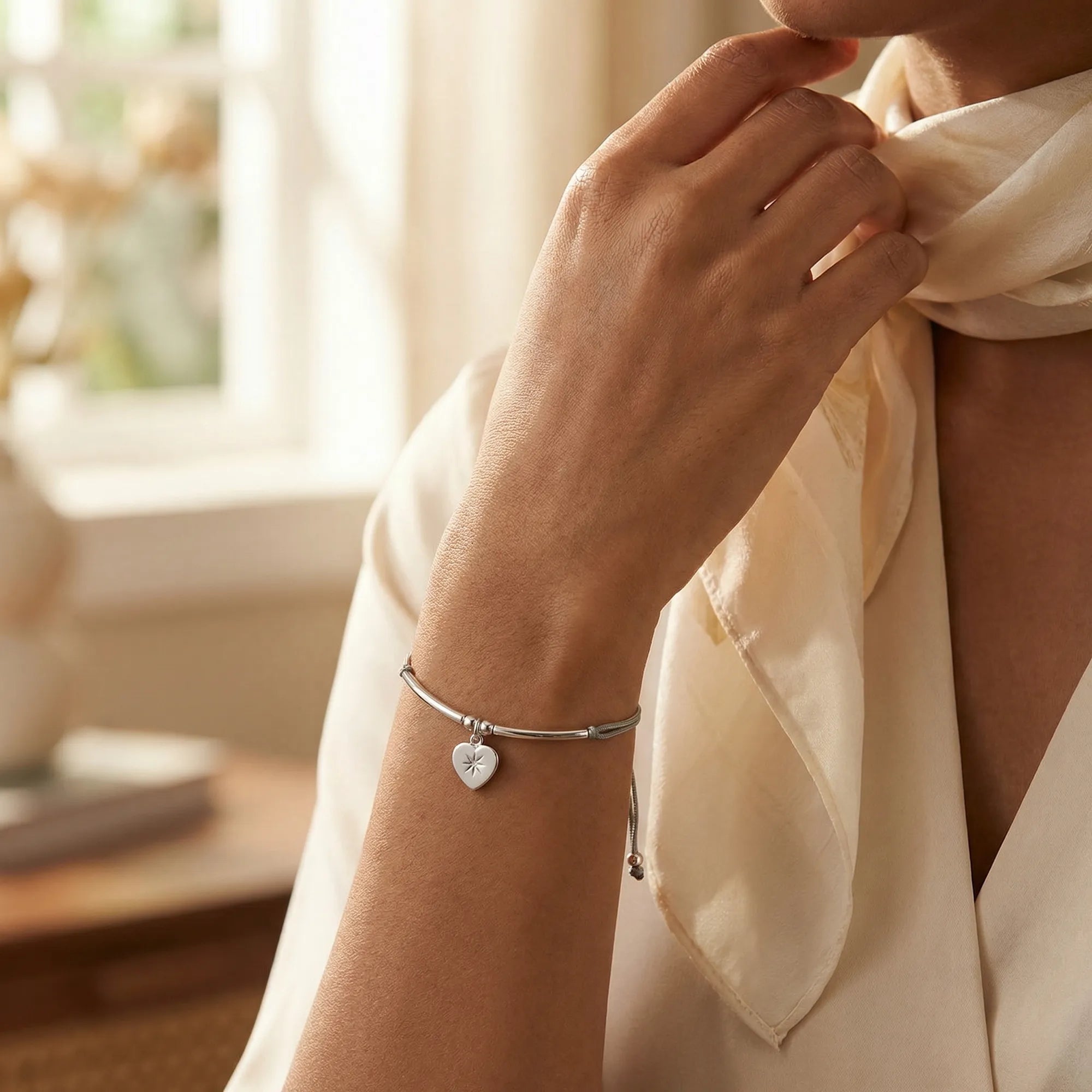 North Star heart silver bracelet worn on the wrist with a silk scarf, adjustable grey cord, Dubai UAE