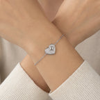 North Star heart bracelet worn on crossed wrists in cream knit styling — micro-pavé CZ and raised star charm rhodium silver