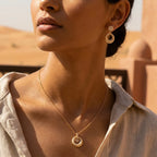 Matte ring and floating disc drop earrings and pendant in 18K gold worn in desert UAE setting — olive skin model