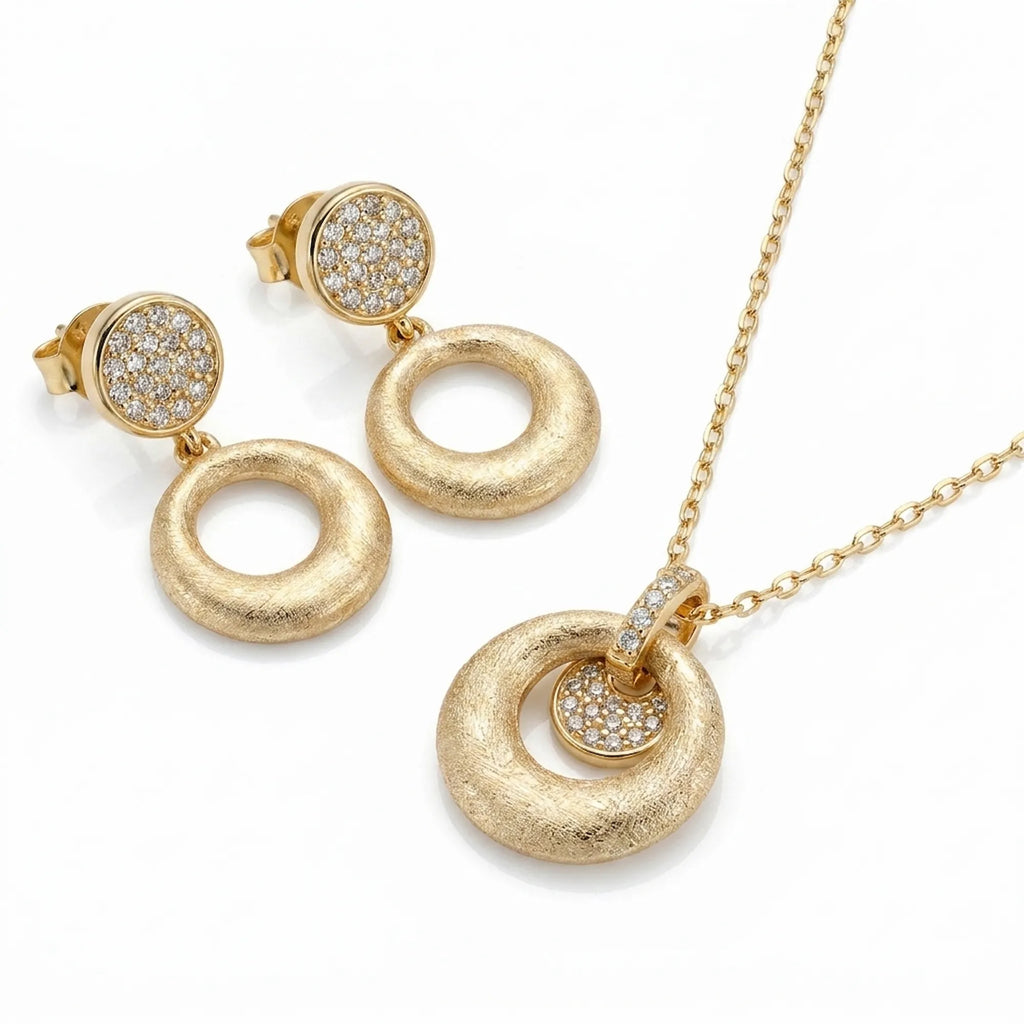 Brushed 18K gold orbiting disc pendant necklace and circle drop earrings in 925 sterling silver — white background