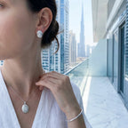 Rhodium silver oval pendant necklace and stud earrings worn with Burj Khalifa in background — Luna Dura Dubai