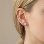 Model wearing the cubic zirconia pavé heart stud earring alone in 925 sterling silver, side profile of the ear.
