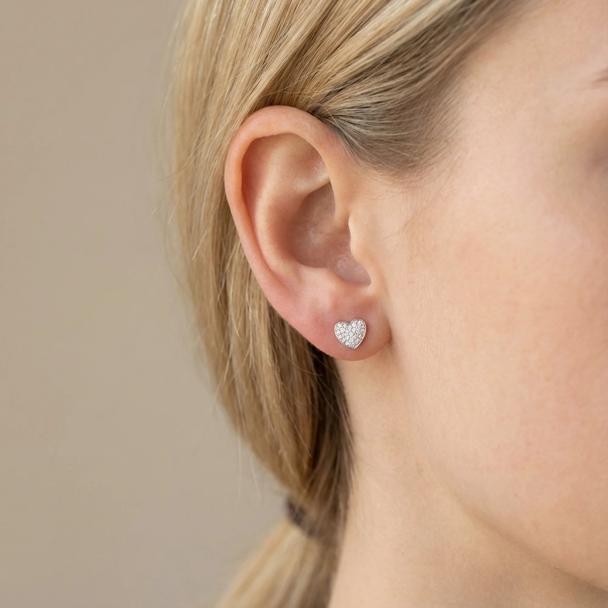 Model wearing the cubic zirconia pavé heart stud earring alone in 925 sterling silver, side profile of the ear.