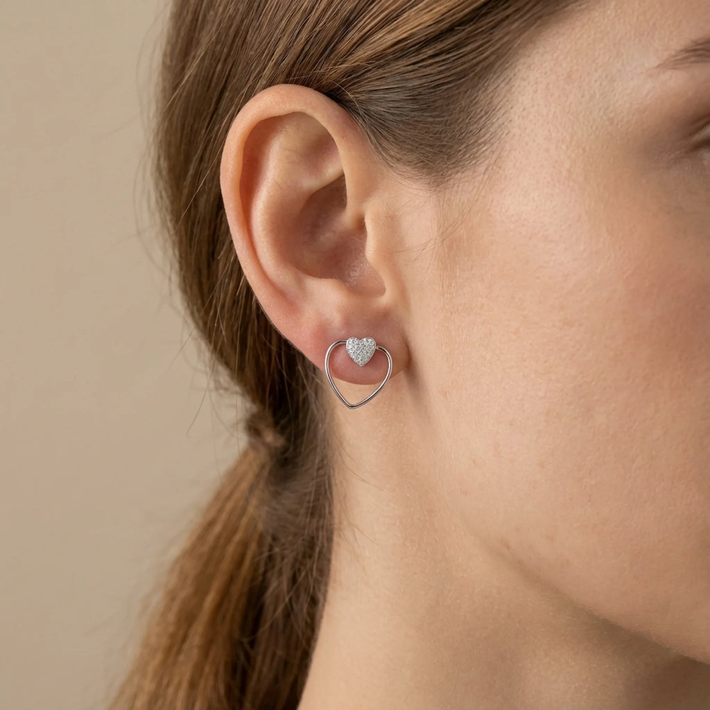 Model wearing the pavé heart stud with the open heart wire frame encircling the earlobe, in sterling silver.