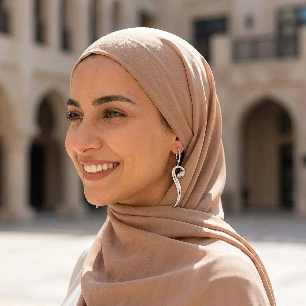Paved serpent drop earrings on hijab model — Gulf heritage arched courtyard, green CZ eye detail visible, 925 silver