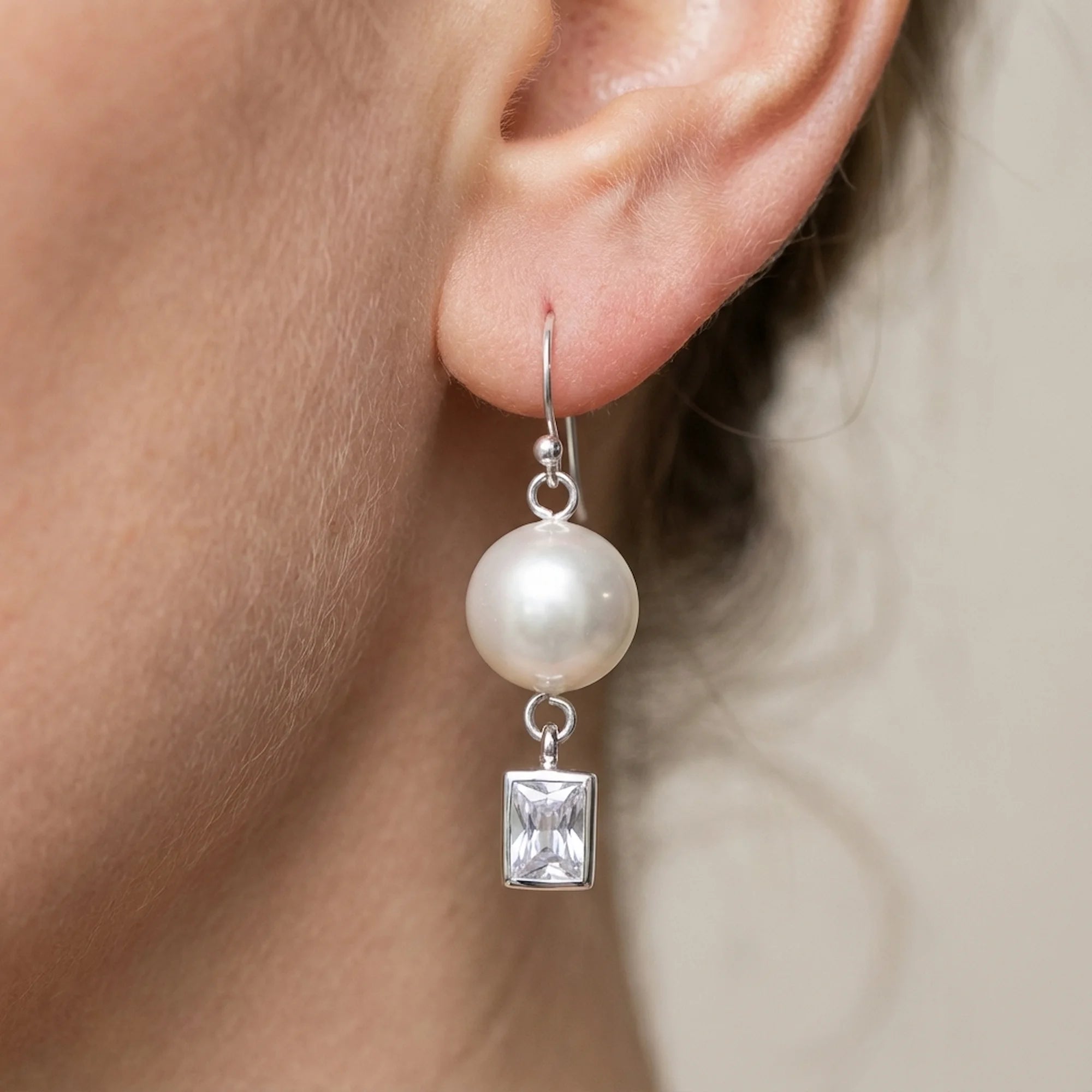 Silver pearl and cubic zirconia drop earring on a shepherd hook worn on an ear