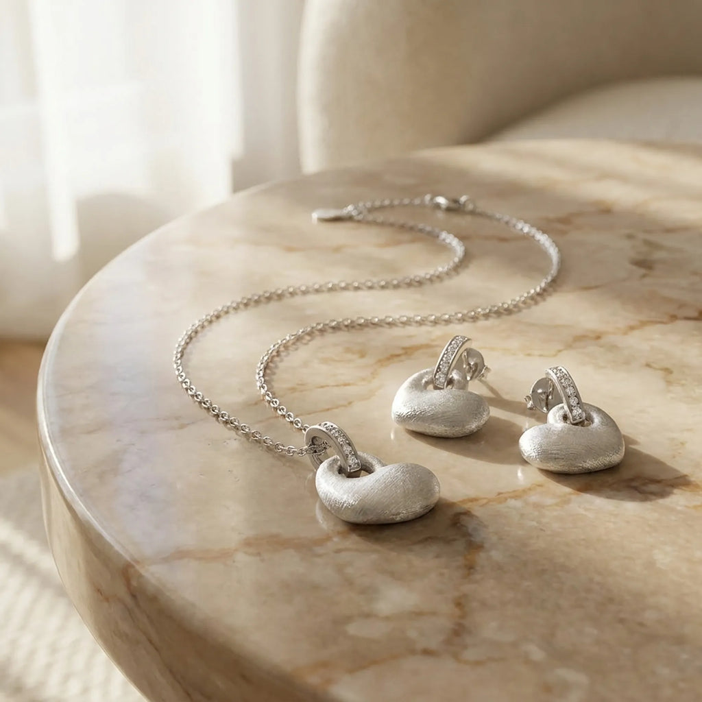 Rhodium silver puffed heart pendant and drop earring set on marble surface — editorial gifting display Dubai