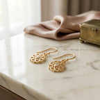 Gold vermeil radial pierced-disc earrings with cubic zirconia on a marble surface in Dubai.