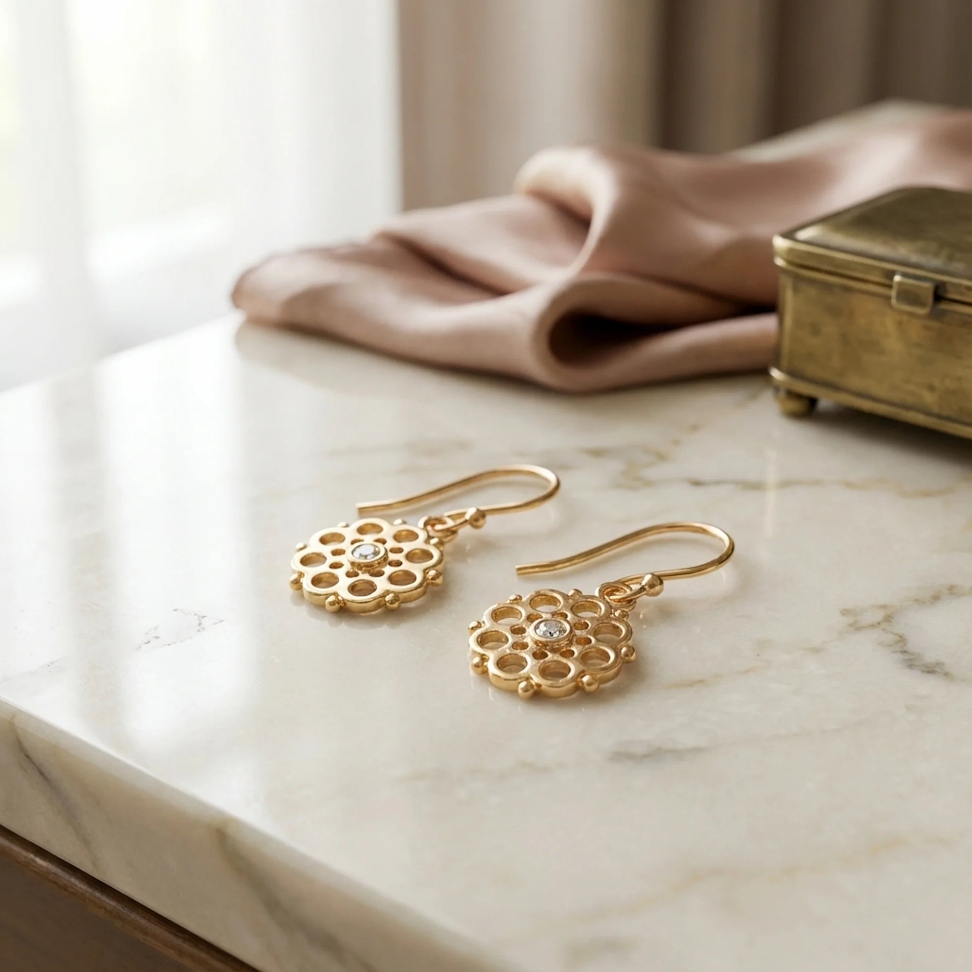 Gold vermeil radial pierced-disc earrings with cubic zirconia on a marble surface in Dubai.
