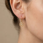 Close-up of a woman in Dubai wearing a gold vermeil radial pierced-disc earring with cubic zirconia.