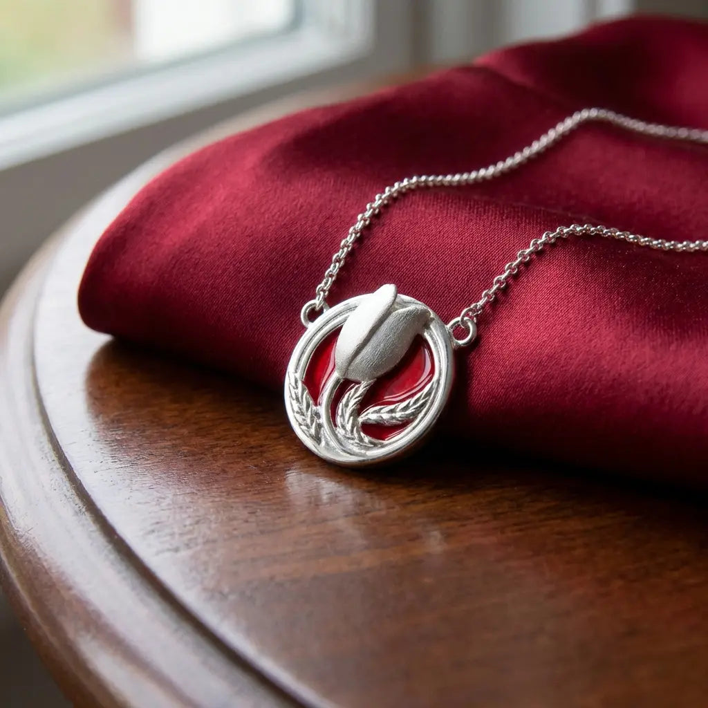 Close-up detail of a silver red tulip necklace resting on deep red velvet, showcasing the intricate metalwork and enamel.