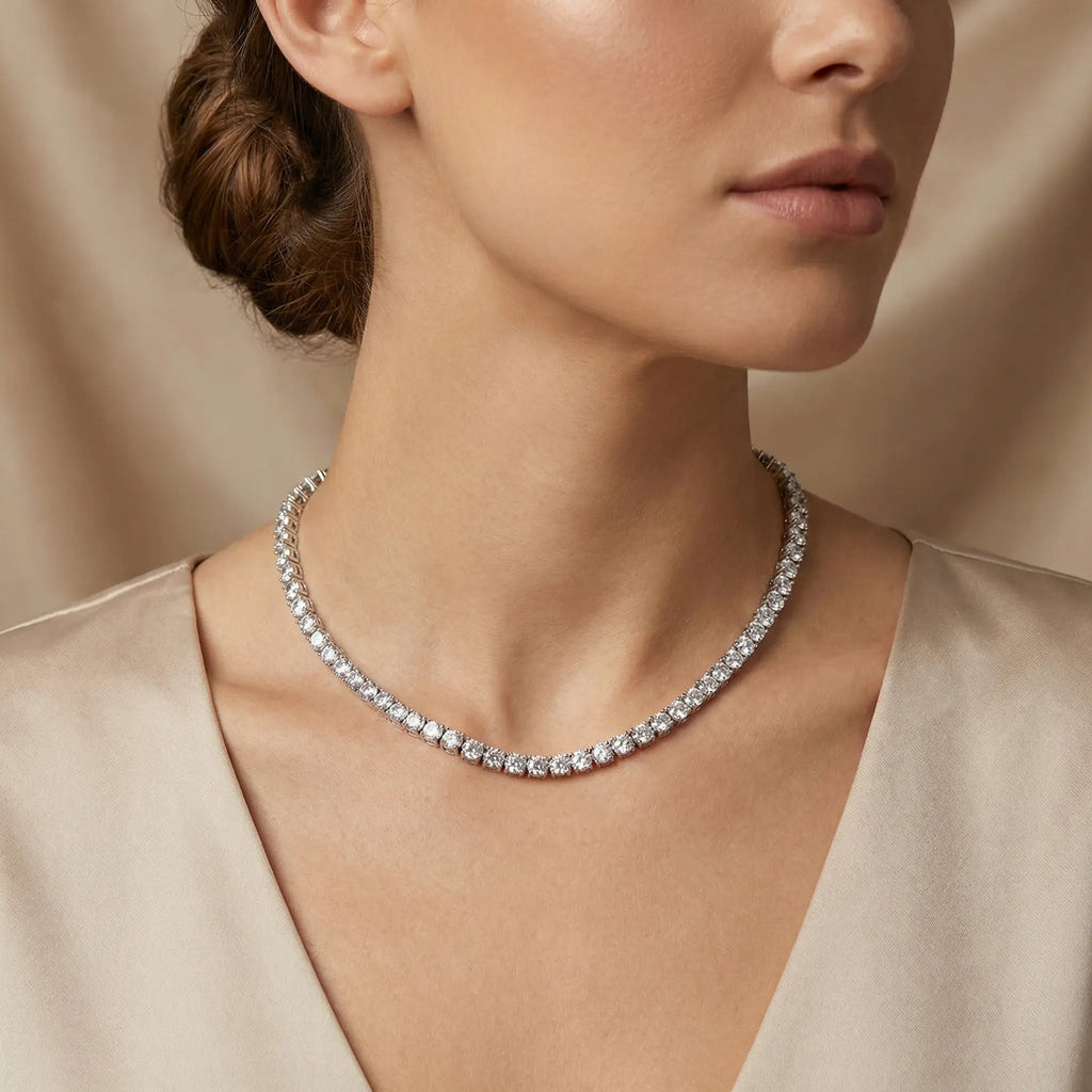 Rhodium-plated tennis necklace with brilliant white cubic zirconia stones worn by a model against a soft silk backdrop