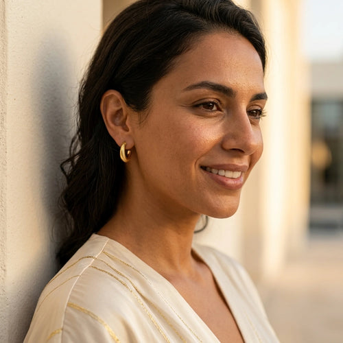 Woman wearing 18K gold vermeil crescent moon hoop earrings outdoors in DIFC Dubai.