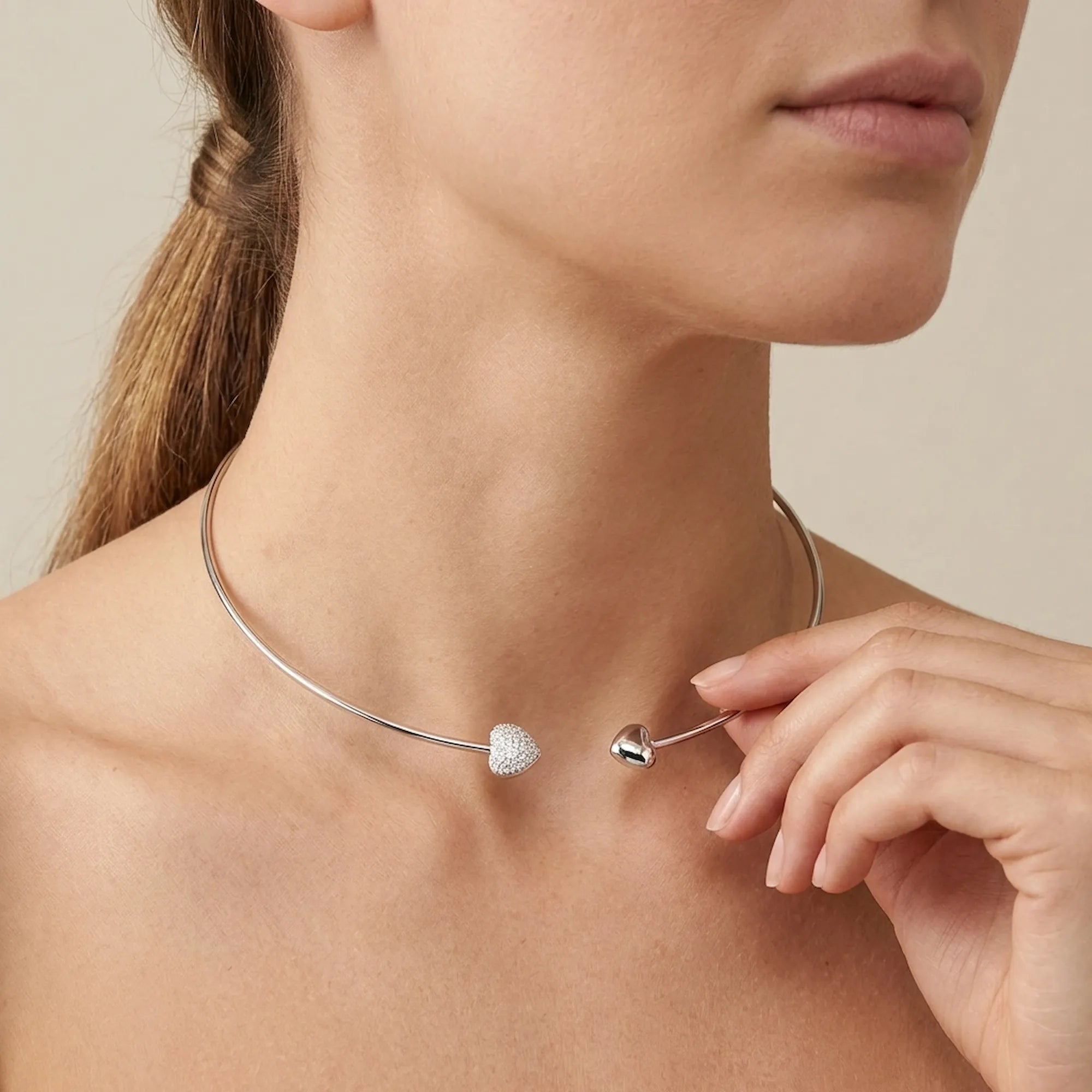 Close up of a woman adjusting the plain heart locket choker, demonstrating the fit, scale, and elegant placement on the neck.