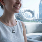 Woman wearing silver sea turtle Mother of Pearl necklace indoors with Museum of the Future visible through window Dubai
