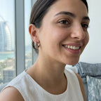 Woman wearing rhodium-plated 925 silver crescent moon hoop earrings with the Burj Al Arab in Dubai.