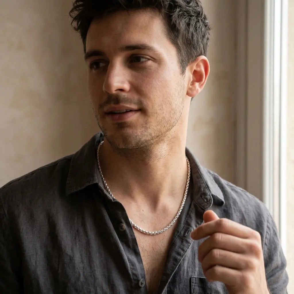 Model wearing a bright silver-tone chain necklace with an open-collar charcoal shirt.