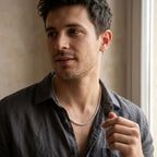 Model wearing a bright silver-tone chain necklace with an open-collar charcoal shirt.