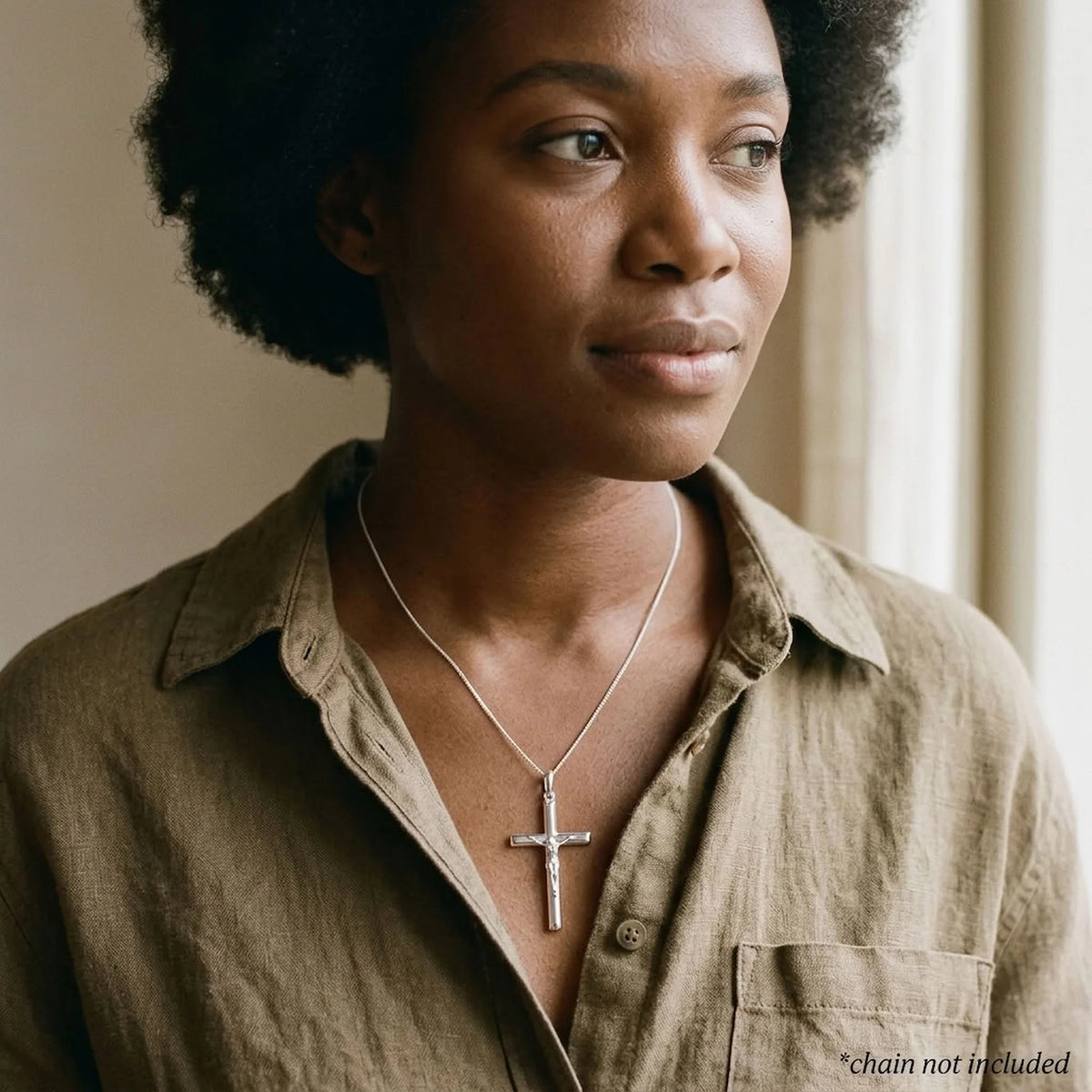 Woman wearing a mirror-polished sterling silver crucifix pendant with raised Corpus, chain not included.