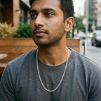 Man wearing a textured silver-tone curb-link chain necklace over a grey T-shirt.