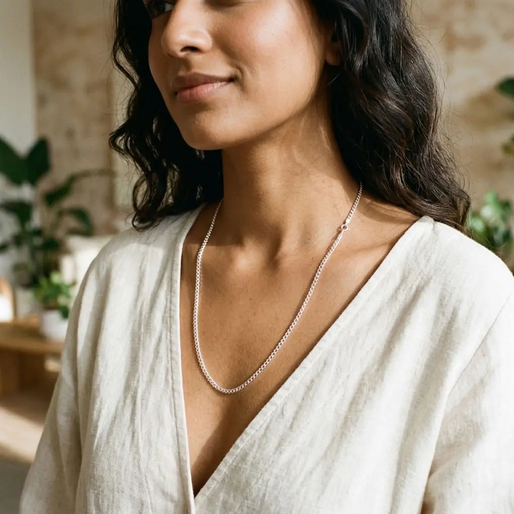Woman wearing a textured silver-tone link necklace with a cream V-neck top.