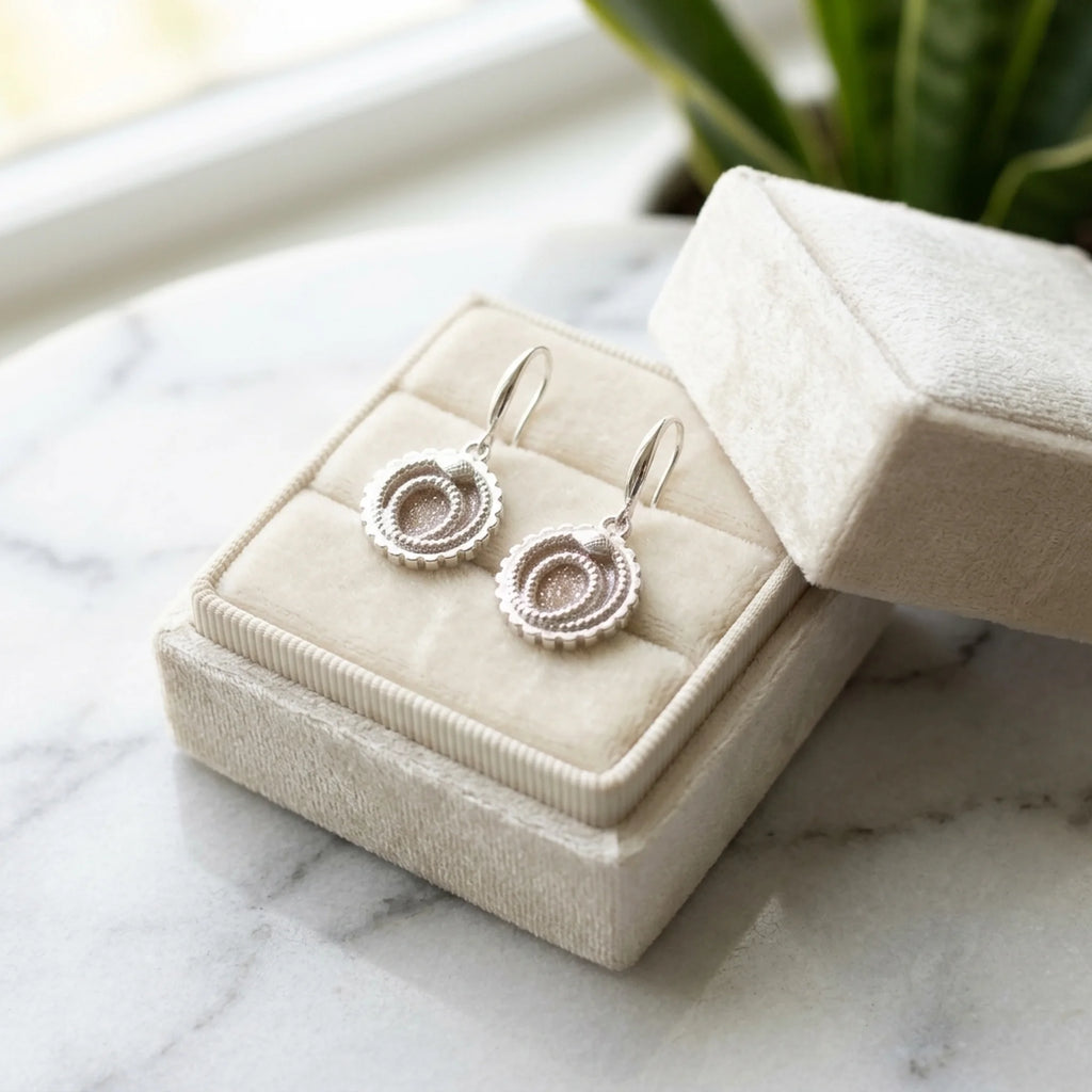 Ivory silver enamel ouroboros snake drop earrings featuring a toothed cog border inside a velvet box in Dubai.