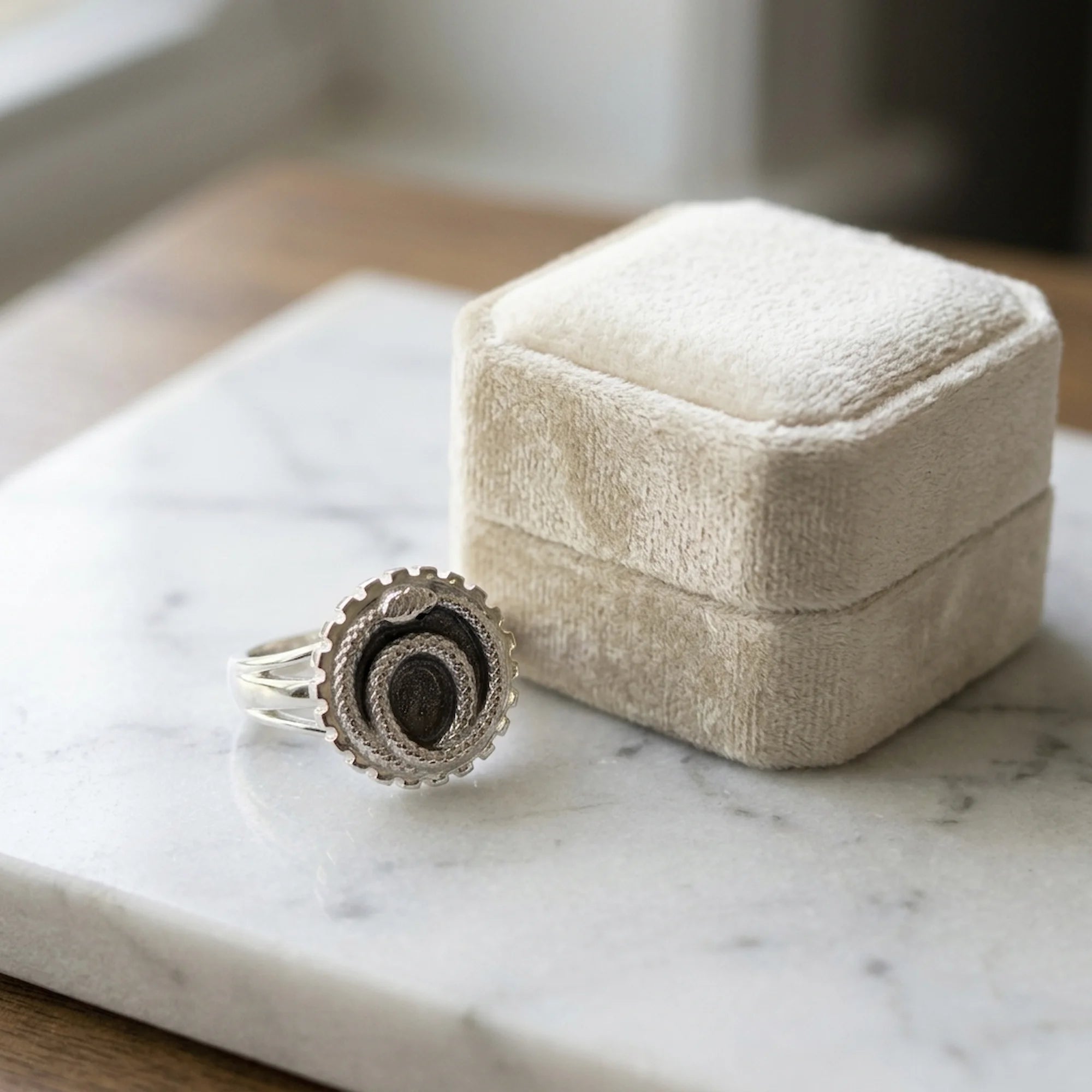 Ivory silver enamel ouroboros snake signet ring in 925 sterling silver resting near a jewellery box in Dubai.