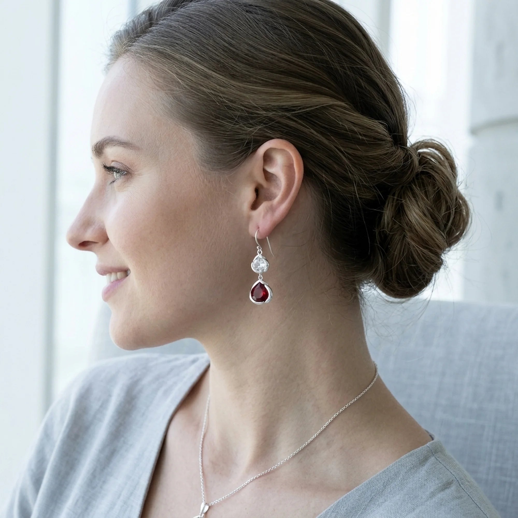 Smiling woman wearing the silver lab-grown ruby lotus drop earrings, an elegant July birthstone gift in Dubai.