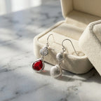 Lab-grown ruby and white topaz lotus drop earrings in 925 sterling silver beside a velvet jewellery box in Dubai.
