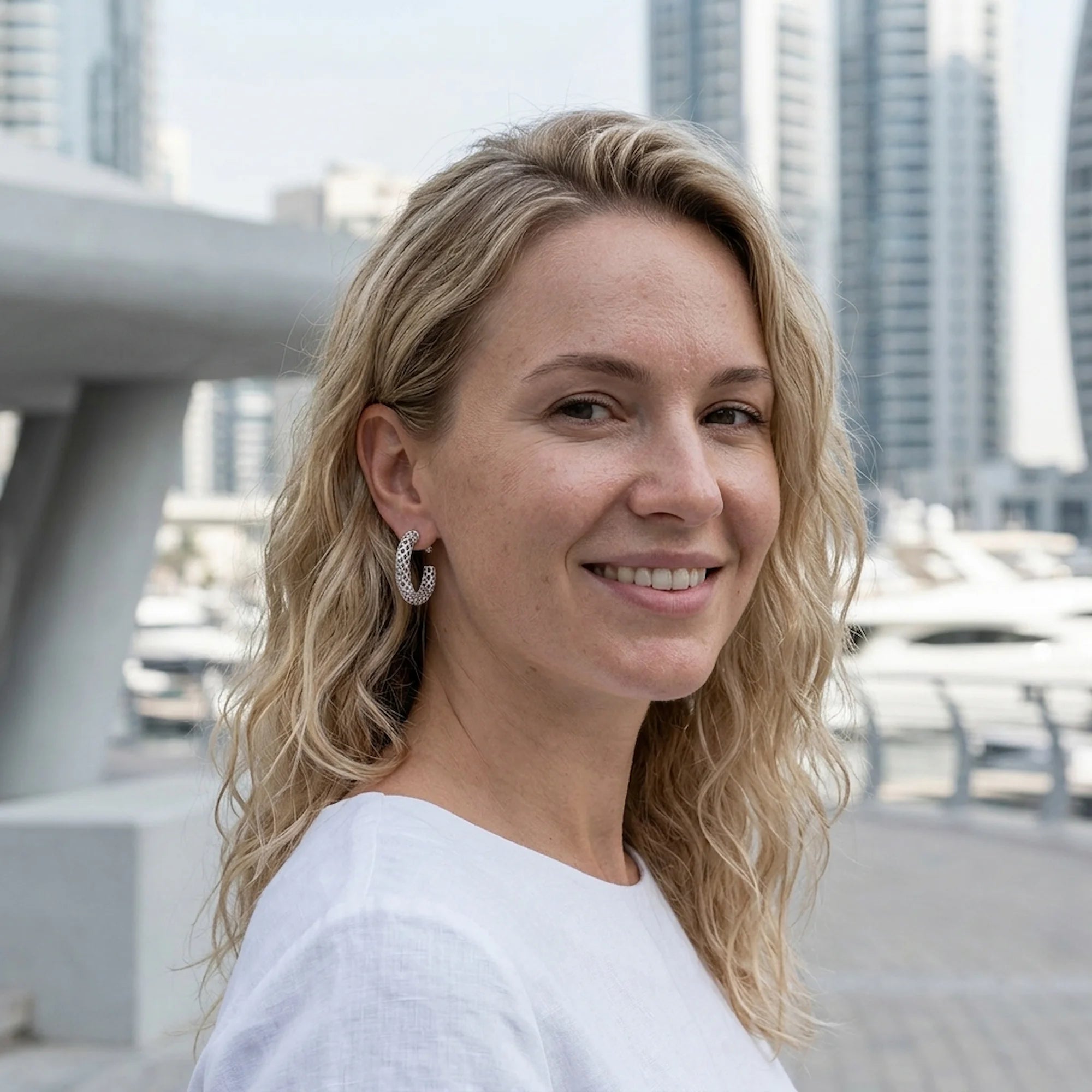 Woman wearing sterling silver lattice hoop earrings with cubic zirconia outdoors in Dubai.