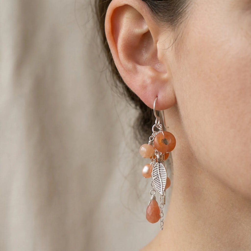 Model wearing our 50mm long 925 sterling silver leaf chain drop earrings featuring warm matte peach natural stones for size reference.