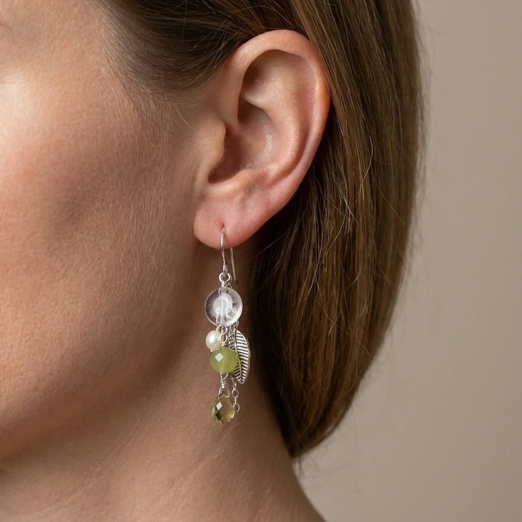 View the elegant 50mm drape of our 925 sterling silver leaf chain drop earrings with lime green natural stones worn on a model's ear.
