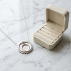 Silver ouroboros snake pendant with a cog border resting near a jewelry box, a 925 sterling silver milestone gift in Dubai.