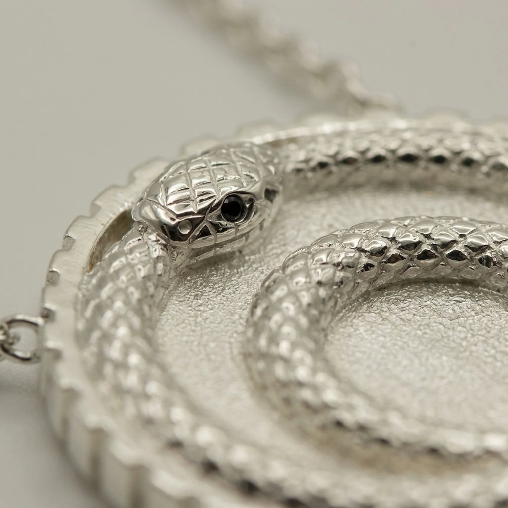 Silver ouroboros snake pendant featuring a double loop and blue topaz eye in 925 sterling silver, a milestone gift in Dubai.