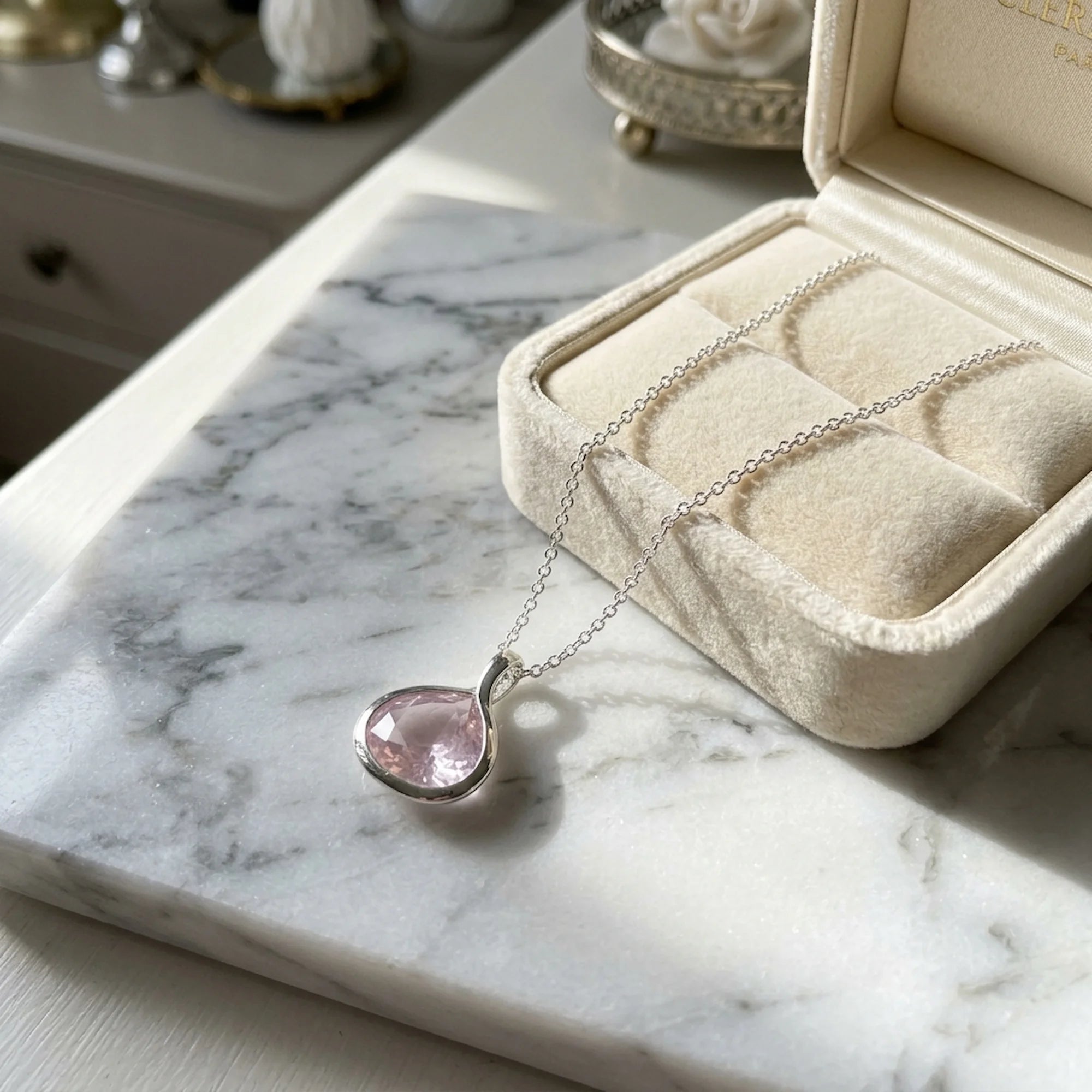 Natural rose quartz lotus pendant necklace in 925 sterling silver beside a velvet jewellery box in Dubai.