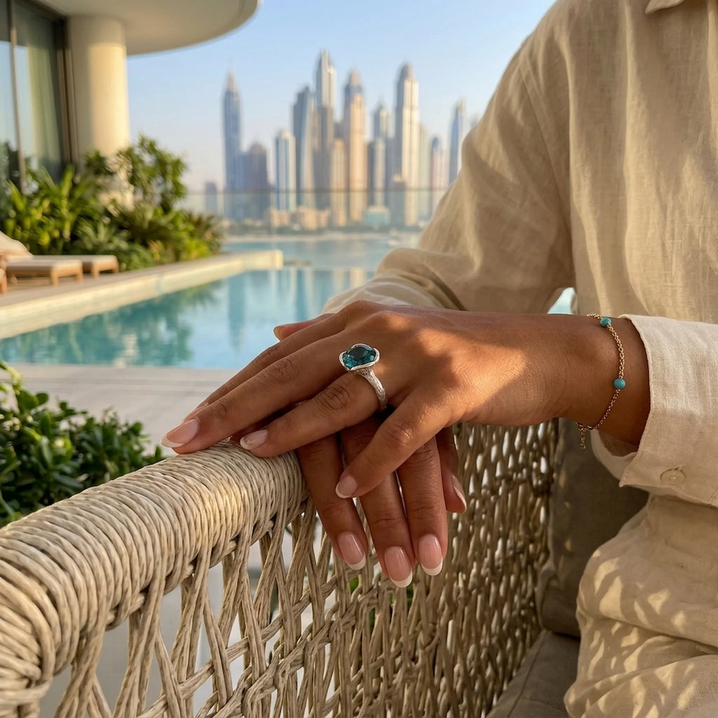 Woman wearing the 9-carat natural sky blue topaz lotus cocktail ring in 925 sterling silver on a balcony in Dubai.