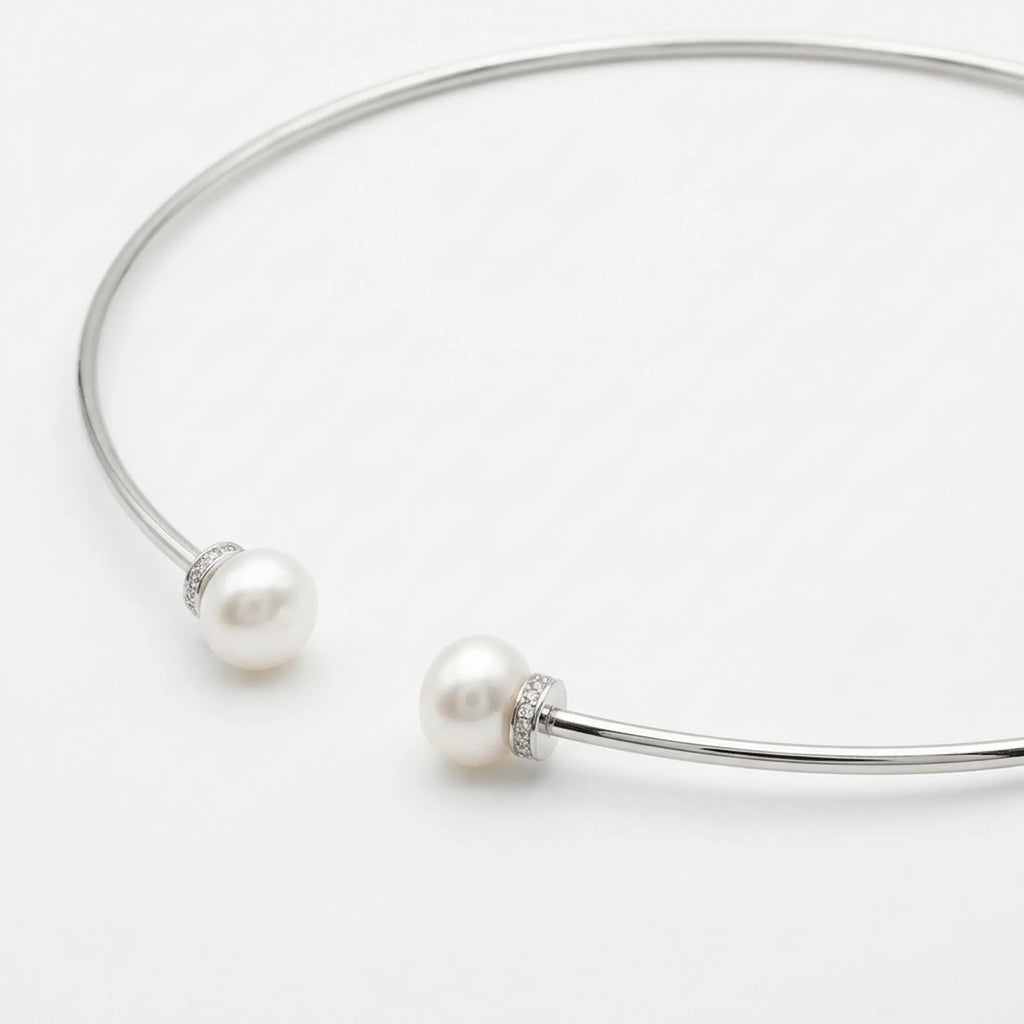 Extreme close-up of the 10mm fresh water pearls and intricate cubic zirconia pave setting on the sterling silver torque necklace collar.