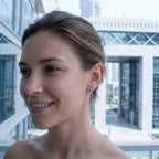 Silver V-shape pave CZ drop earring worn on the ear against DIFC towers, modern look, Dubai UAE