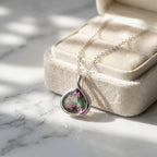 Silver watermelon tourmaline simulant lotus necklace in 925 sterling silver draped over a velvet box in Dubai.