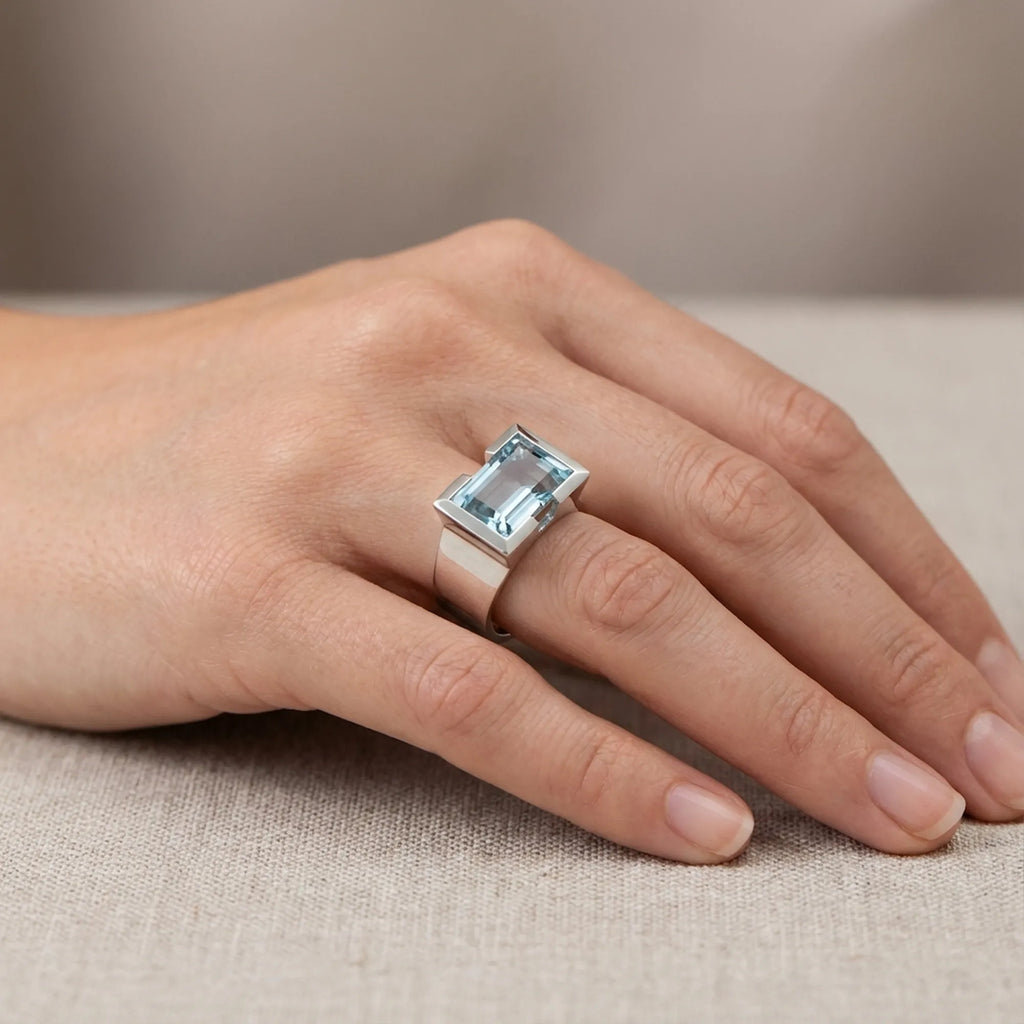 Natural sky blue topaz statement ring worn on hand against linen fabric — 925 sterling silver architectural half-bezel setting